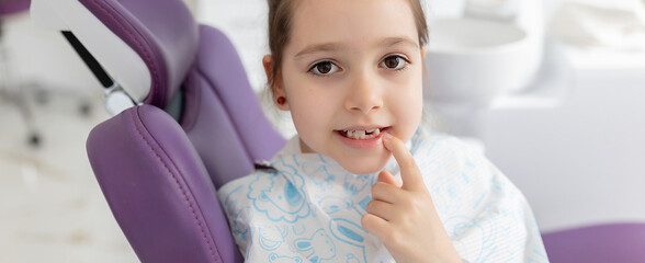 Cute little girl showing her milk teeth at dental office, and waiting for a checkup. Early...