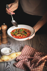 Appetizing minestrone with asparagus sprouts on a fresh bun on a light wooden background