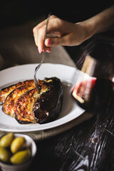 Food photography. Baked eggplant with olives and cheese on a dark wooden background