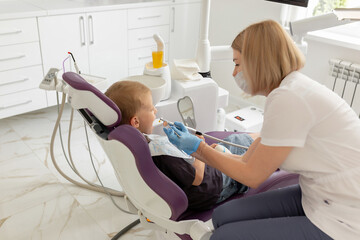 Dentist examining little boy's teeth in clinic