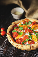 Appetizing pizza with tomatoes and cheese on a dark wooden background. Slice of pizza with stretchy cheese