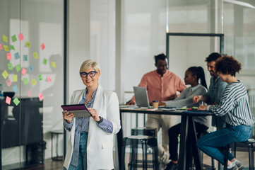 Obraz premium Portrait of a business woman standing in a office with colleagues in the back