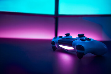 Low angle view game controller on table. Blank dual display and pink wall in background.