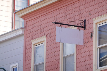 A blank white extending from a house with pink wooden shingles