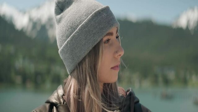 Blonde young woman wearing a beenie sipping a warm drink on a cruiseship outside traveling through Alaska. Close Up. Front Angle. Anamorphic