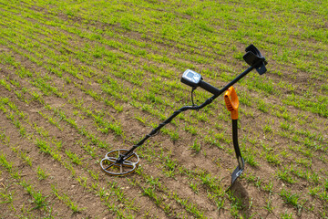 Fototapeta na wymiar Modern metal detector. Sensor for searching for metal underground. Metal detector and shovel without anyone. Treasure search equipment on ground with grass. Treasure hunting equipment