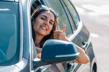 woman in car with thumb up