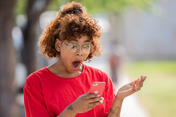 african american girl looking at mobile phone or smartphone surprised