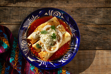 Fried potato tacos called flautas with red sauce and cheese. Mexican food