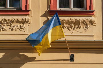 National flag of Ukraine on the yellow wall of an old house on a sunny day in the historical center of Prague, Czech Republic, European solidarity with the fight against Russian military aggression