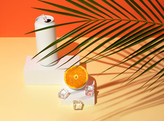 White painted can with ice and orange fruit on product podium with tropical palm leaf. Summer drink minimal concept.