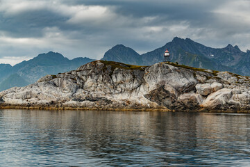 Norwegian seascape, lighthouse on the island, rocky coast with dramatic skies, the sun breaks through the clouds, sheer cliffs, small islands illuminated by the sun