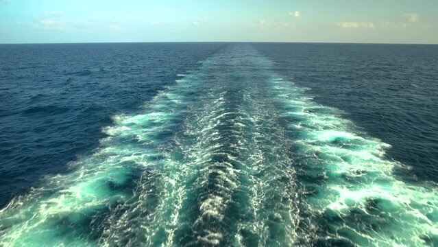 Wake of vessel. Trace from ship. Ocean water. Wide wake trail from boat. Back view. Deep green blue.