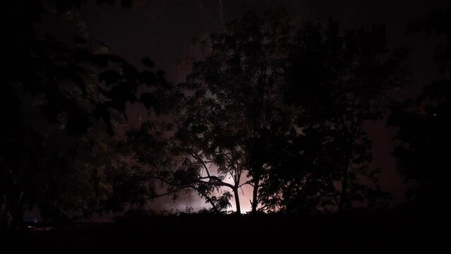 Overloaded transformer burns on side of raid and emits bright flashes of lights during rainstorm on a cold wet night in New Jersey