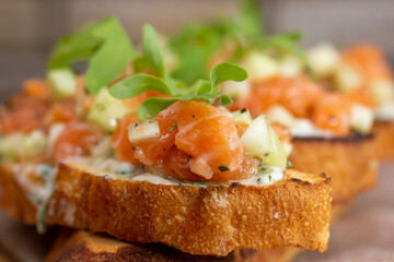 dry aged smoked salmon on the slices of bread and cream cheese sandwiches with cherry tomatoes and rocket salad