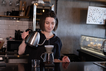 charming brunette woman barista making filter coffee in coffee shop. brewing coffee in cafe