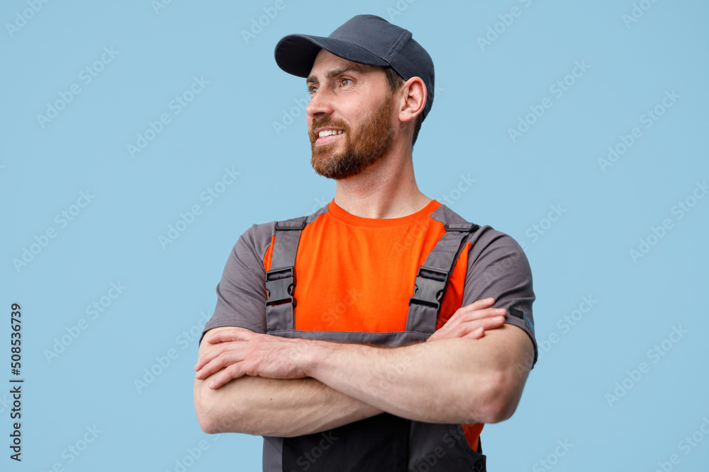 Wall mural Portrait of smiling workerman in uniform with crossed hands looking at side