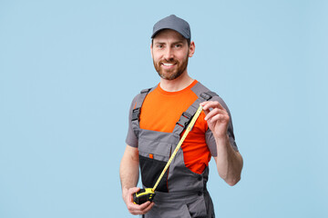 Smiling repairman worker in uniform holding measure tape and looking camera 