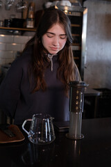 pretty brunette girl making aeropress coffee in modern coffee shop