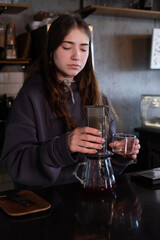 pretty brunette girl making aeropress coffee in modern coffee shop
