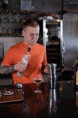 Barman is making cocktail at night club. stylish young man mixing a cocktail in a dark loft cafe. alcohol drink in modern bar. male bartender