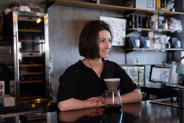 charming brunette woman barista making filter coffee in coffee shop. brewing coffee in cafe
