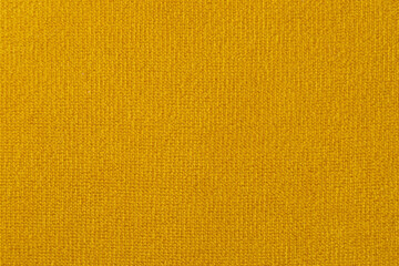 wide yellow upholstered armchair with fabric upholstery on wooden legs in retro style