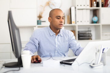 Adult businessman working in office with laptop, sitting at desk
