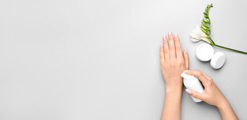 Young woman applying hand cream on light background with space for text, top view