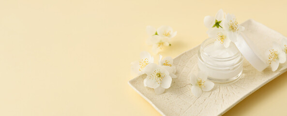 Jar of cream and jasmine flowers on color background with space for text