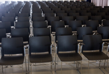 Rows of black plastic chairs in conference hall