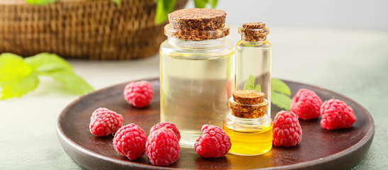 Bottles of raspberry essential oil on table, closeup
