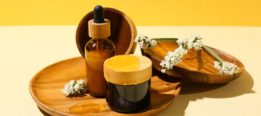 Composition with cosmetic products, flowers and honey on color background