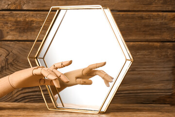 Decorative hand with mirror on wooden background