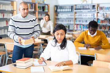 Young adult woman working with books, finding information at library