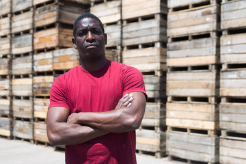 Portrait of serious pensive African male in red t-shirt standing in storage