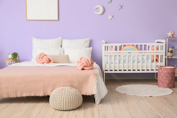 Interior of bedroom with comfortable bed and crib near violet wall