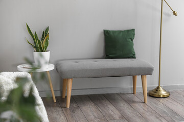 Soft bench with cushion and table near light wall