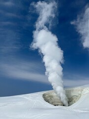 Steam rises from a fumarole on a snowy volcano