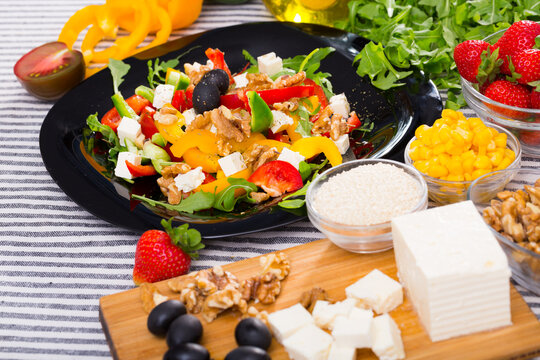 Image of ready-made salad and its ingredients on the table indoors.