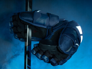 Closeup of ice hockey equipment against a smoky background. Hockey puck, ice hockey stick, ice hockey gloves
