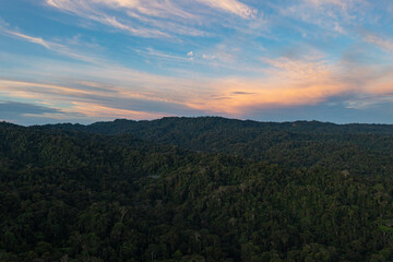 Fototapeta na wymiar Stunning aerial view of a tropical forest with a beautiful and colored cloudscape due to the sunset - Nature background of a forest