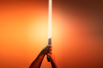 a fantastic laser sword lightsaber in the hands of a man - 508542519