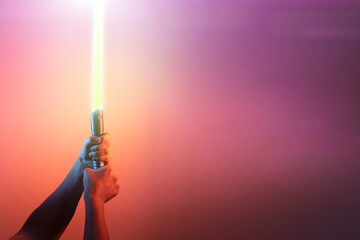 a fantastic laser sword lightsaber in the hands of a man - 508542529