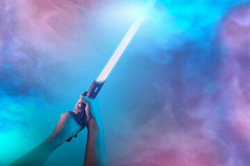 a fantastic laser sword lightsaber in the hands of a man - 508542544