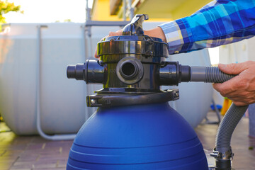  pool Filter. Swimming pool cleaning equipment.Blue water filter in the hands of a man in a blue...