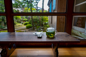 古民家カフェにある歴史を感じる寺子屋机と硝子ポットの中に入ったフレッシュハーブティと硝子のティーカップ