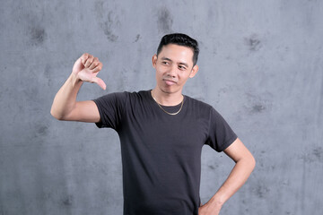 An Asian man showing condescending expressions and gestures on a gray studio background	
