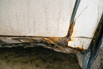Rusted white car sills close-up. The effect of reagents in winter on an unprotected car body