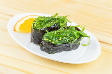 sushi with seaweed in a plate placed on a wooden floor